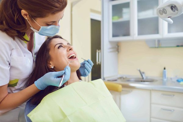 A girl with a beautiful smile with a dentist indoors.